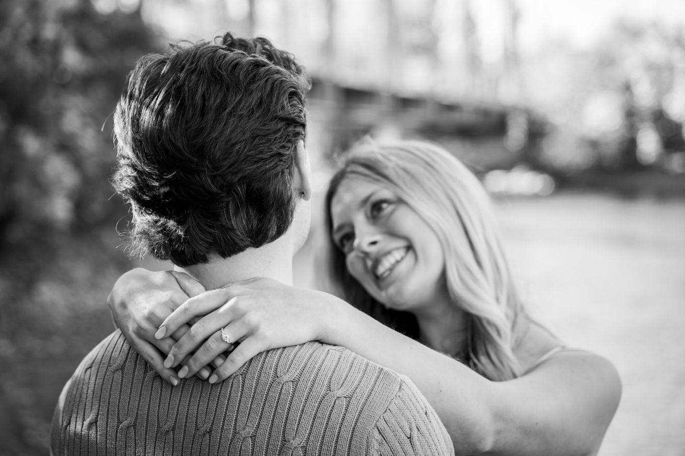 Black-and-white photo of a woman looking up at her fiancé, ring visible